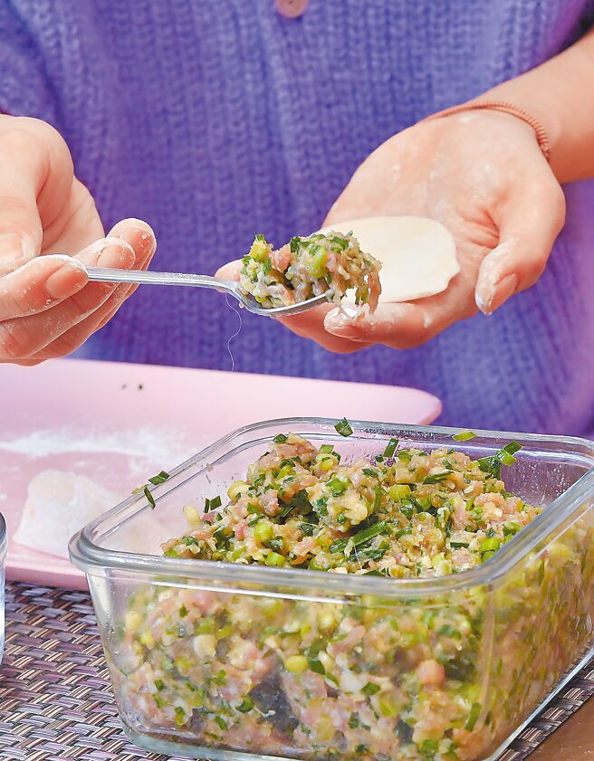 连晨翔把事先准备好的内馅包进饺子皮。（卢祎祺摄）