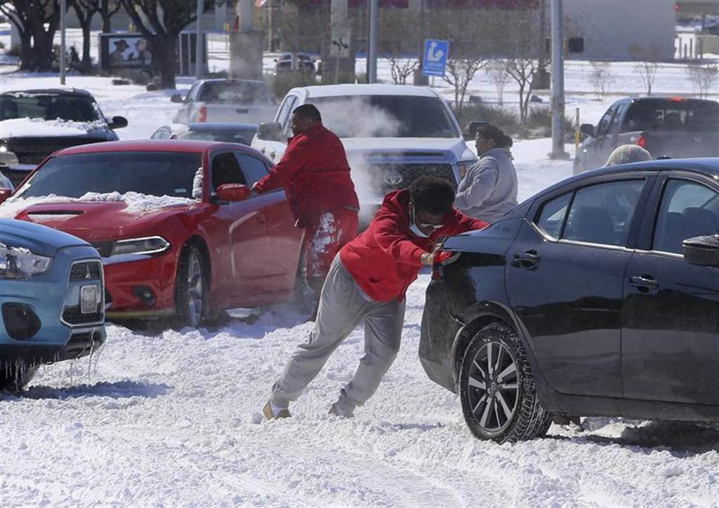 德州罕見嚴寒，大部分車輛都因油箱結凍熄火，駕駛只能以人力推車。(美聯社)