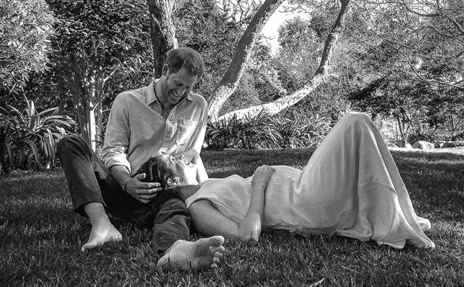 哈利王子和梅根宣布，將迎接第二個孩子，圖為梅根躺在哈利膝上，秀出凸起的小腹。（路透）