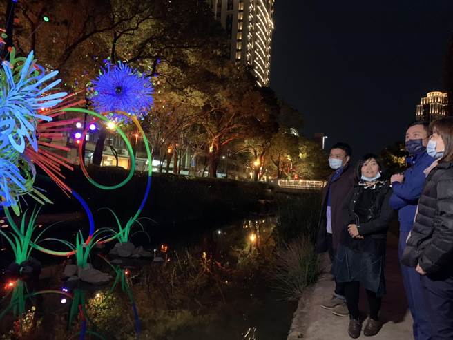 新竹市政府邀请新竹子弟艺术家蔡筱淇夫妇（左一、左二）创作「风．光．逐梦」艺术灯饰，作品宛如「凝结烟火」绽放在护城河面上。（陈育贤摄）