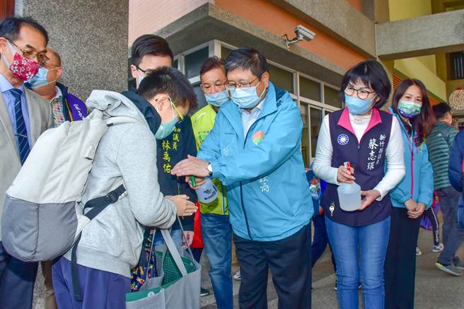县长杨文科（中）到东兴国小门口视察防疫，贴心帮小朋友们喷酒精消毒手部。（罗浚滨摄）