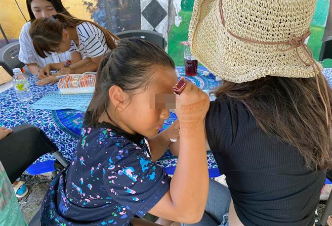 排湾族学童「小萱」神情专注地为旅客手臂彩绘Henna图案。（世展会提供）