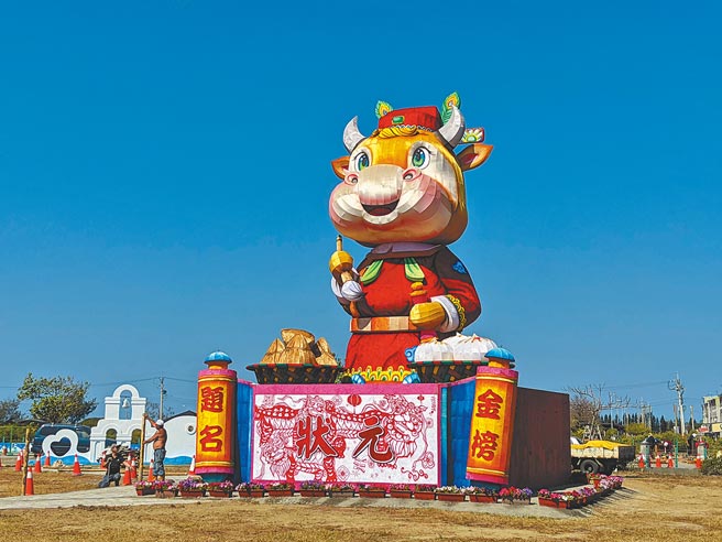 台湾灯会4层楼高的副灯「犊站金榜」移置到台南北门游客中心外的大草坪，26日元宵夜将点灯展示，金牛头戴状元帽、手拿文昌笔，造型可爱，相当吸睛。（庄曜聪摄）