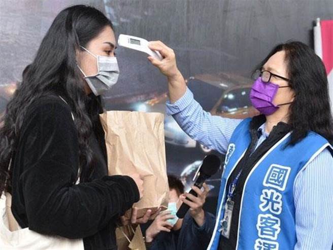圖為國光客運人員替乘客量測體溫的情況。圖／國光客運提供