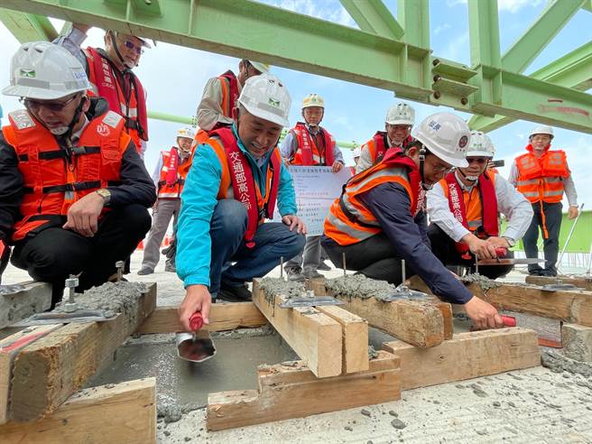 林佳龙与杨镇浯在合拢的大金边桥P50至P51上构节块工区，联手砌上最后一块混凝土，进行溼接缝抹平工程施作。（县府提供）