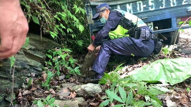 來自雲林的陳姓夫婦25日駕駛車輛在台東知本樂山產業道路上失控打滑，車子左側兩個輪胎陷入山溝動彈不得，員警在輪胎底下墊上石塊協助車輛脫困。（蔡旻妤攝）