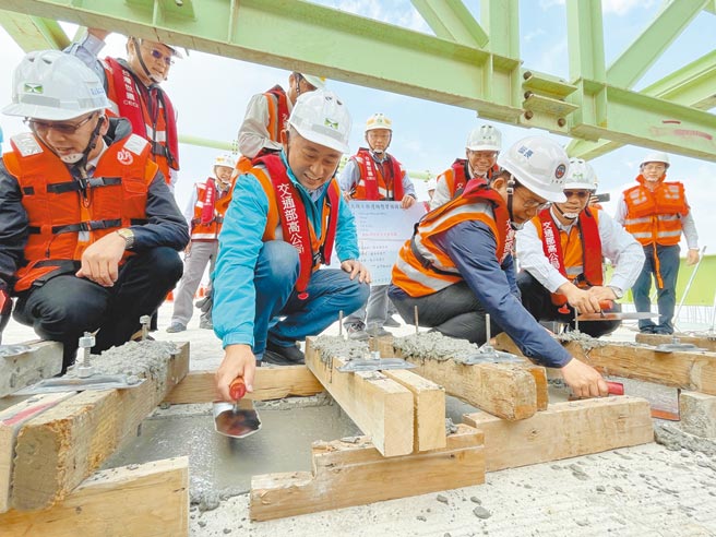 林佳龙（前右）与杨镇浯（中）参与溼接缝抹平工程，象徵金门大桥从此迈向新的里程。（县府提供／李金生金门传真）