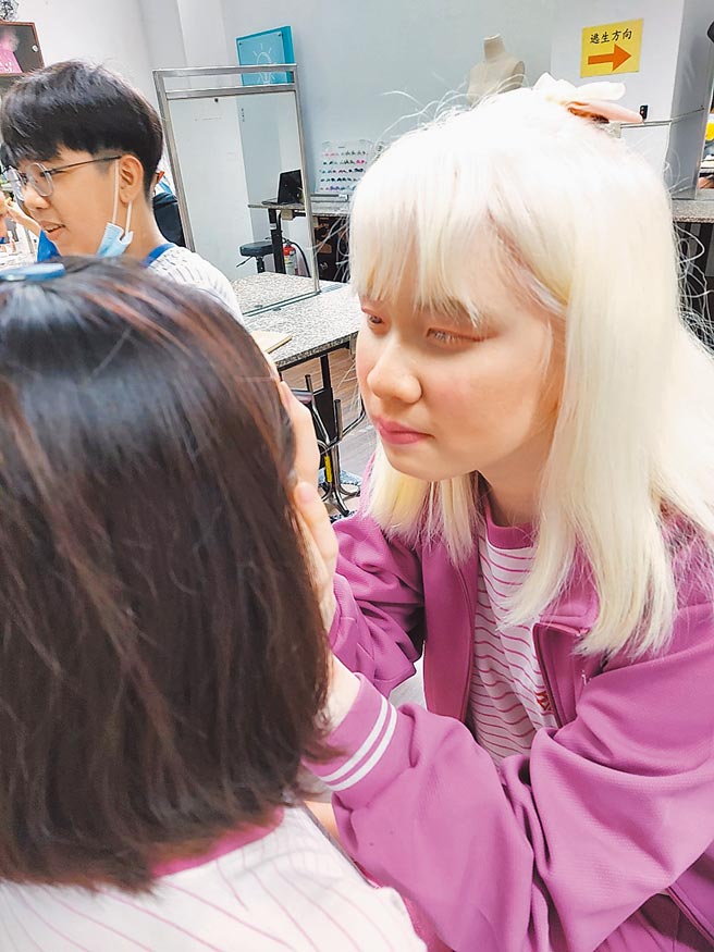 新北市福和国中学生忻紫瑄（右）为白化症患者，视力近乎全盲，仍凭藉细腻笔触，为一张张脸孔画出美丽妆容。（福和国中提供／许哲瑗新北传真）