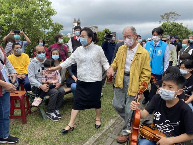 县长徐榛蔚（左）牵着廖丙盛（右）的手，一起走向和平钟。（罗亦晽摄）