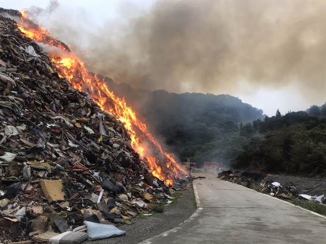 新北市环保局八里掩埋场后方巨大家具暂置区今天（28）日上午7时许突然起火燃烧，现场窜出大量黑烟。（消防局提供／李俊淇新北传真）