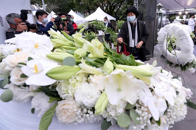 台北市政府28日举办228事件74周年纪念会，出席民眾将百合花放在纪念碑文上，吊念当年牺牲生命的罹难者。（黄世麒摄）