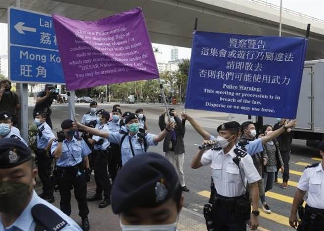香港西九法庭下午場外氣氛緊張，在場香港警員高舉港區國安法的紫色警告旗，同時舉起藍旗。（取自東網）