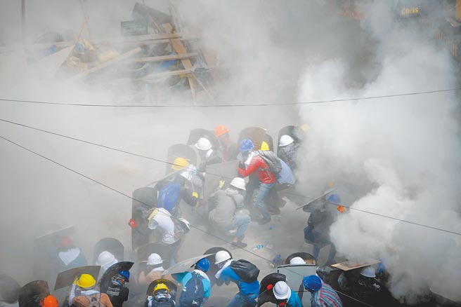 缅甸镇暴警察1日再度动用闪光弹和催泪瓦斯，驱散带着盾牌防身的示威群眾。霎时烟雾四起，民眾四散寻找掩护。（路透）