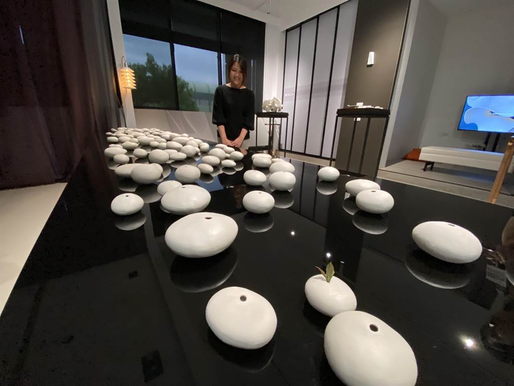 藝術家邱俞鳳「無形無色」開展，會場中受矚目的「卵石」作品，在長桌上一顆顆像河床石頭的卵石，其實是她以白瓷土創作。（盧金足攝） 