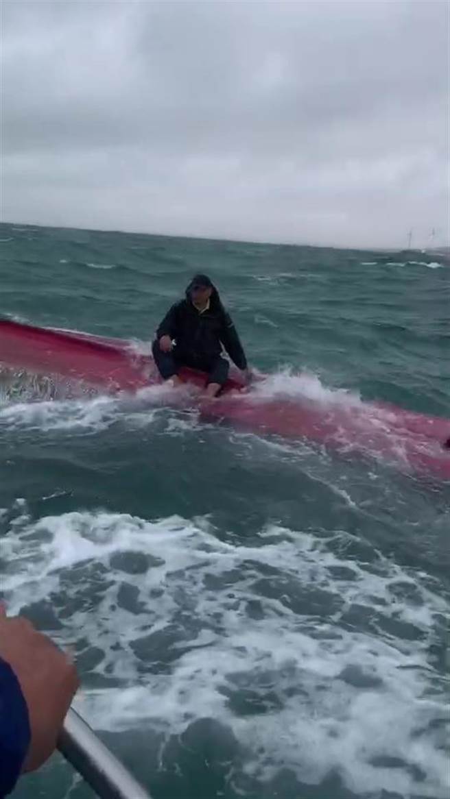 楊姓釣客所乘舢舨被突如其來的大浪打翻，楊某坐在舢舨底待救。（東哥提供／謝明俊苗栗傳真）