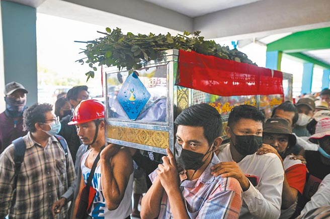 緬甸當局日前血腥鎮壓反政變示威，釀成38死悲劇，掀起國際社會怒火。民眾5日在仰光郊區的墓園，高舉罹難者的棺木，為這位死者送行。（路透）