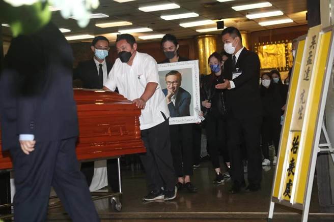 吴韦仑捧着父亲遗照，搭上灵车前往火化场。（星岛日报提供）