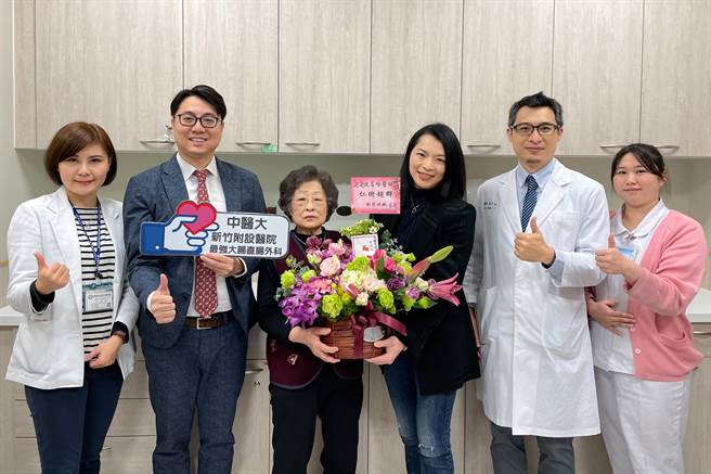罹患超低位直腸癌臨床第三期的81歲阿嬤（左三），獻花感謝直腸外科主任沈名吟（右三）與醫護人員讓她恢復健康。（羅浚濱攝）