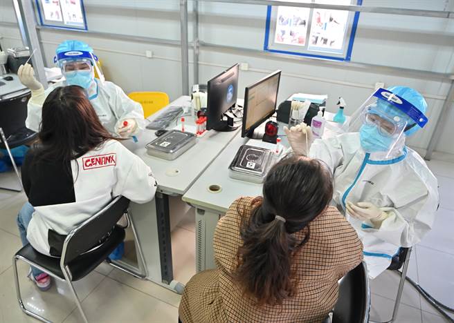 香港疫情严峻，北京市政府关于核酸检测的新规定指出，自本月15日零时起，由香港直航入境北京的旅客，必须持有港府认可的7天内核酸检测无感染报告。图为两位女士在内蒙古医科大学附属医院进行核酸检测採样。（中新社）