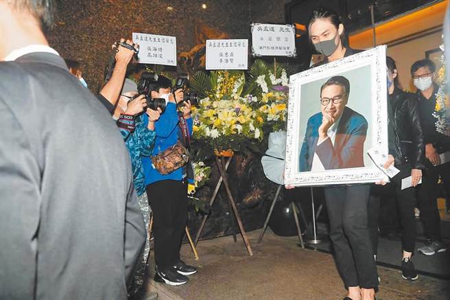吴韦仑捧着父亲遗照，搭上灵车前往火化场。（星岛日报提供）