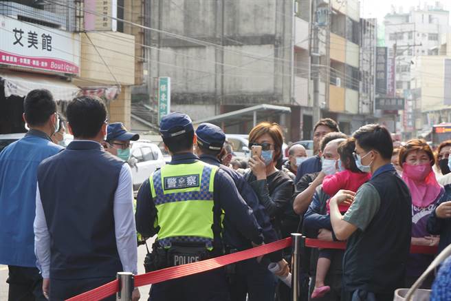 戴墨镜、口罩的石冈反徵收联合自救会长李蔚慈，出现在维安管制区人群中，警方上前劝离。（王文吉摄）