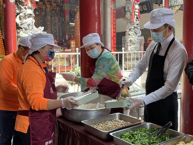 新竹市于本月2日起陆续恢復关怀据点、共餐食堂等服务，市长林智坚（右）10日特别到港南好邻居关怀协会了解开站现况，并帮长辈打菜。（陈育贤摄）