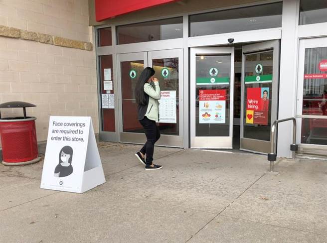 美国德州州长取消口罩令，不少商家仍要求客人戴上口罩。图为一名戴口罩的女子走进达拉斯市北郊一家商店，店门口放着要求顾客戴口罩的告示。（新华社）
