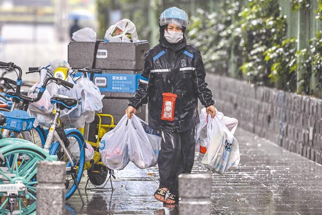 當外送員，不少兩岸青年以此為兼職。圖為一名廣州外賣員在雨中配送物品。（中新社）