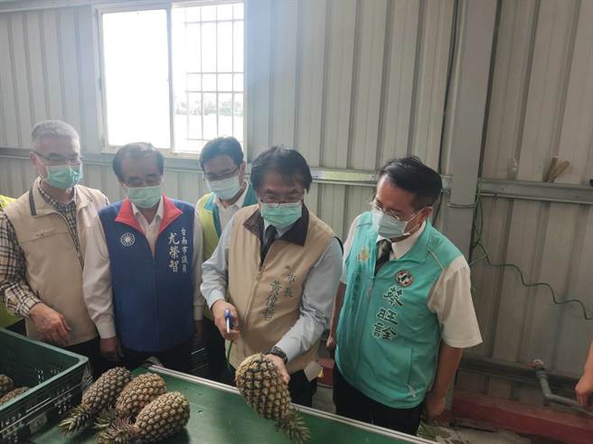 黃偉哲視察鳳梨水洗設備及處理流程，並親自拿著噴槍，體驗清除鳳梨表皮的工作。（劉秀芬攝）