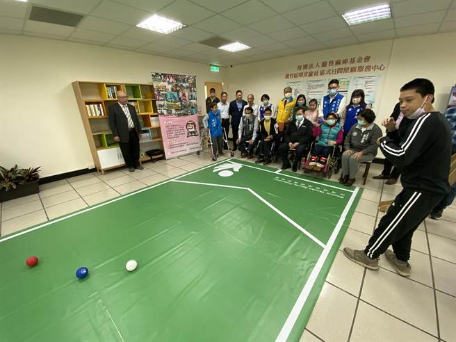 蘆竹區嘻皮廬日照中心13日揭牌，有教練與裁判證的體大應屆畢業腦麻生張亦辰（右一），指導桃園市長鄭文燦（右四）等人體驗地板滾球運動。（蔡依珍攝）