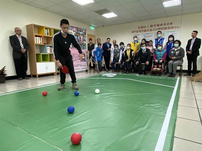 蘆竹區嘻皮廬日照中心13日揭牌，有教練與裁判證的體大應屆畢業腦麻生張亦辰（左二），指導桃園市長鄭文燦（右四）等人體驗地板滾球運動。（蔡依珍攝）