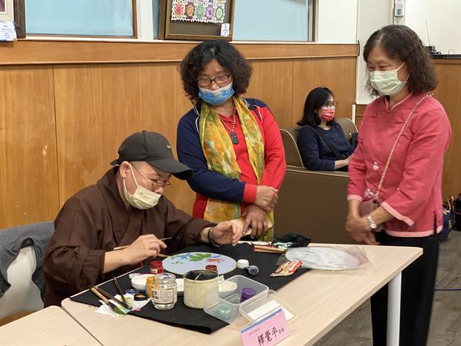陳德黽老師的學生來自社會，參展學員釋悟水師父，也在現場彩繪絹扇吸引賓客駐足欣賞。（吳建輝攝）