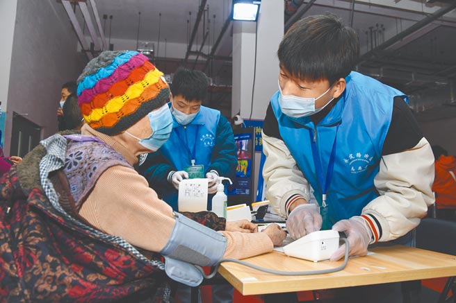 3月14日，在北京市新冠疫苗臨時接種點，工作人員（前右）為社區居民在接種前測量血壓。  （新華社）