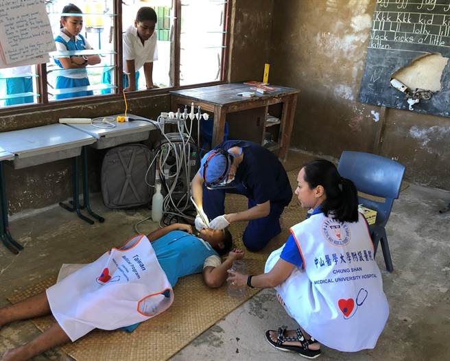 中山附医牙医师到吐国进行口腔卫生保健，因地置宜，没有诊疗椅，直接席地为学童看牙。（中山附医提供／冯惠宜台中传真）