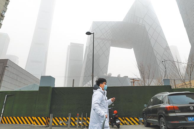 北京市民在沙尘天气中出行。背后央视新大楼有如在雾中。（中新社）