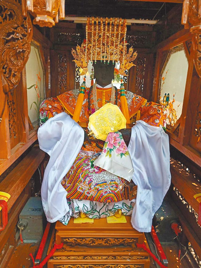 台南开基天后祖庙万历妈首度穿上金履鞋，并手持金扇子出门遶境。遶境配件还有新款LV行动电话耳机包。（洪荣志摄）