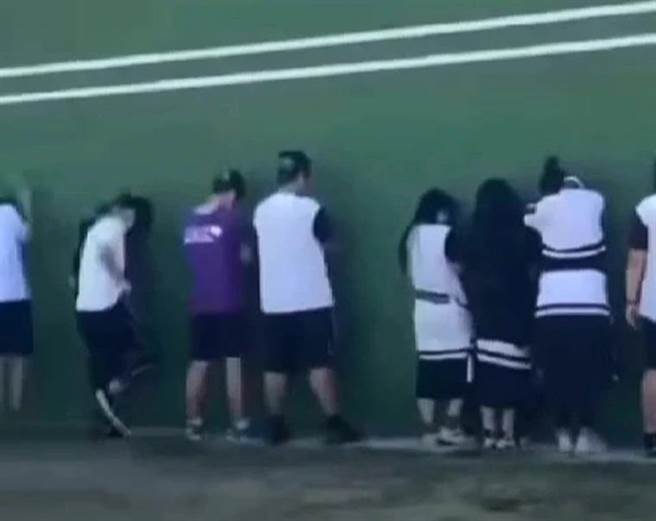 被当成枪靶的8名男女学生，有人举起双手趴在墙上，有人互相靠着缩着身体，还有人作势抚摸痛处。（摘自爆料公社）