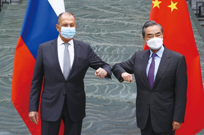 俄罗斯外长拉夫罗夫（左）22日抵达中国访问，中国外长王毅（右）以手肘相碰表示欢迎。图／美联社