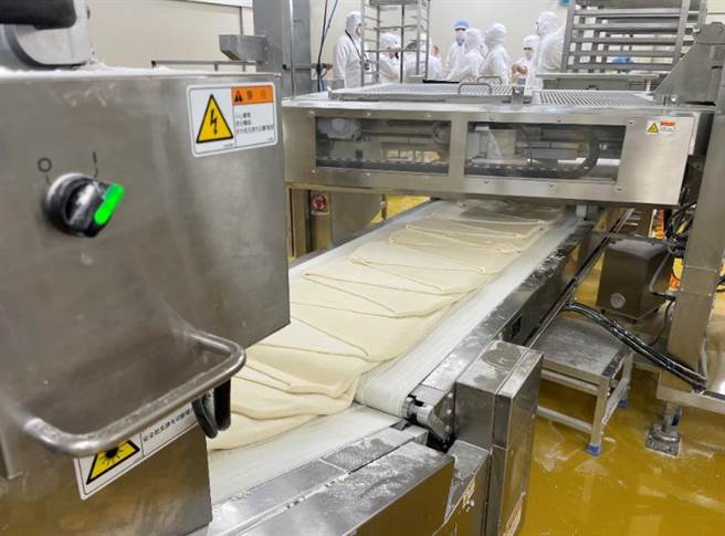 1個小時最高可生產9000個麵包的HM生產線，正在製作帕瑪森麵糰，麵皮層疊出口感，再手工加美奶滋+帕瑪森起司、整型。（郭家崴攝）