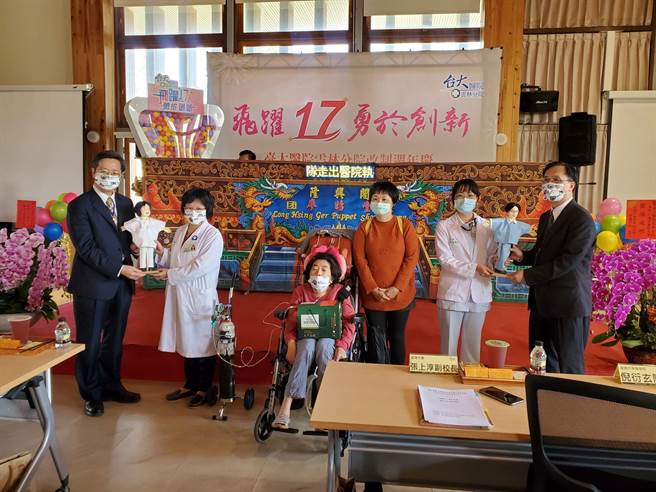台大医院云林分院今（26日）举行改制17周年庆祝大会，台大副校长张上淳（左一）把客制化的布袋戏偶赠给整形外科医师张惠琇（左二），中间坐轮椅的是马小妹，旁边是马妈妈。（周丽兰摄）