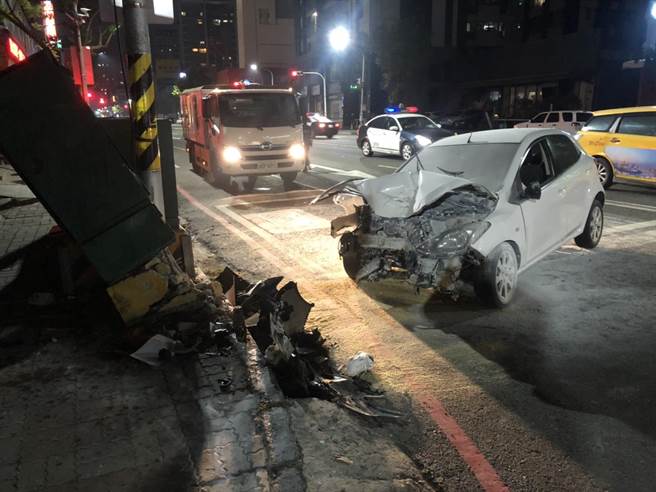 李男駕駛的白色汽車車頭嚴重毀損，附近變電箱也被撞壞。(警方提供／林雅惠高雄傳真)