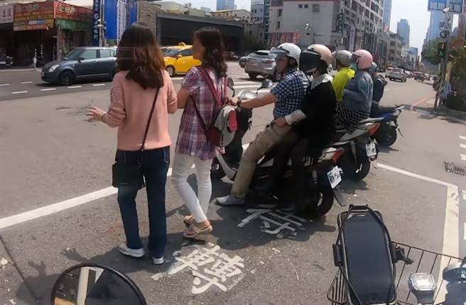 2長髮女與一旁機車併排站在機車待轉區等紅燈。（截自臉書社團《路上觀察學院》影片）