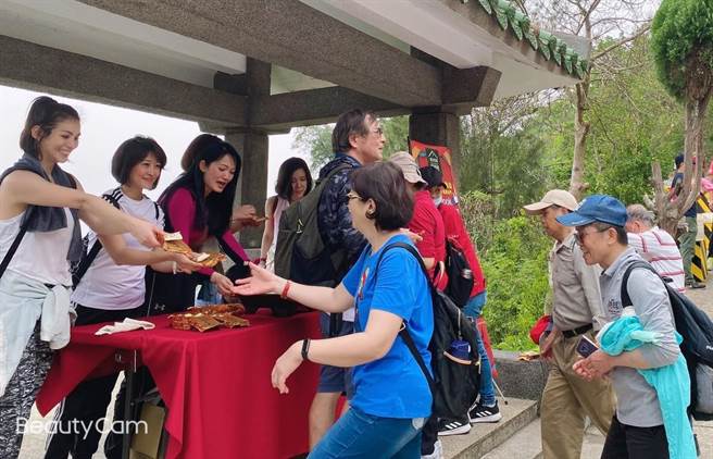 空姐客串「美食推銷員」與遊客分享當地名產貢糖、牛肉乾之二。（聖祖食品提供）