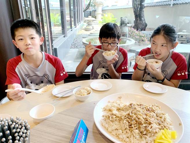 喷水鸡肉饭小雅店负责人董孟婷在儿童节前夕，招待百名兰潭国小学生享用鸡肉饭圆桌餐，今30日中午学童们大口吃着鸡肉饭，直呼又香又好吃！（吕妍庭摄）