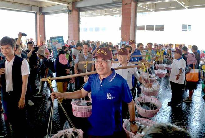圖為2019年10月27日「虱目魚文化節」，時任高雄市副市長的李四川與貴賓肩挑扁擔，象徵著討海人滿載漁獲船隊順航入港熱鬧開場。（圖／取自李四川臉書）