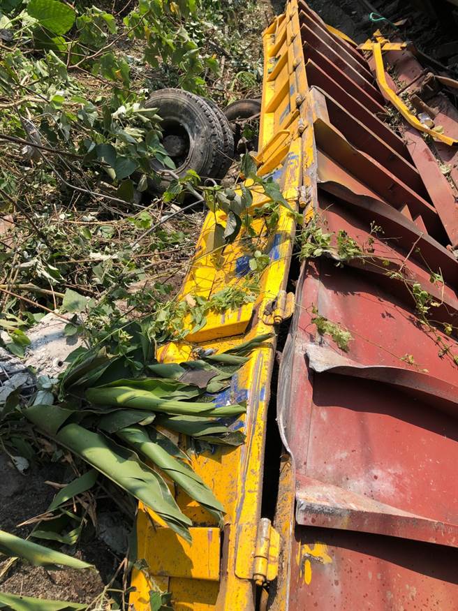 酿成此次事故的工程车跌落一旁草丛，车体呈现翻覆状，不仅轮胎已脱落四散，就连车面板金也已严重受损，根本无法辨认工程车全貌，足以想像事发当下状况有多惨烈。（图／《中天新闻》提供）