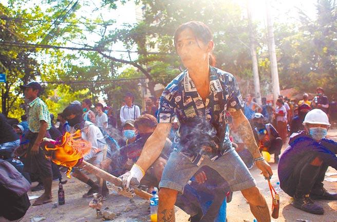 在缅甸最大城市仰光的一场抗议军事政变活动中，一名男子手持火炬站在路障后方与军警对峙。联合国缅甸事务特使警告，缅甸情势濒临失控，演变成内战。（路透）