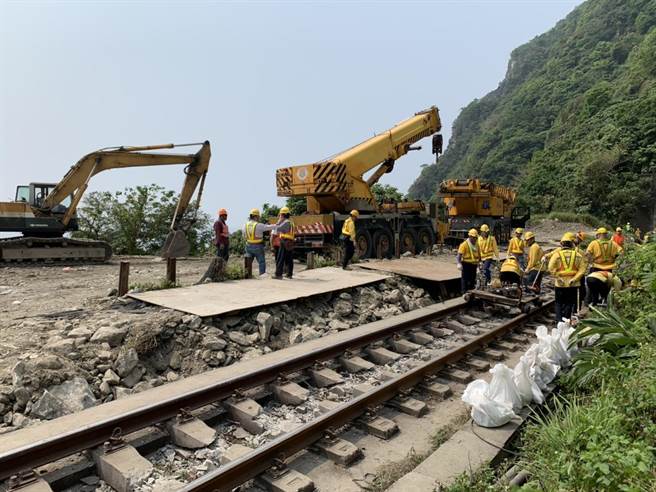 大型机具在现场配合搜索动作，接着调离破损车厢。（王志伟摄）