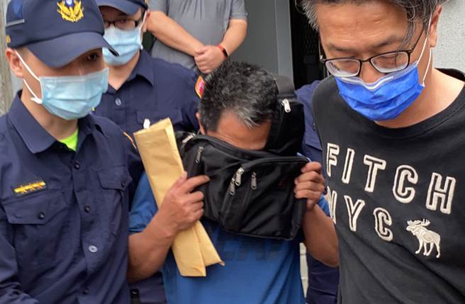 李义祥50万元交保后，在法警与友人护持下，用包包遮脸走出地院。（罗亦晽摄）