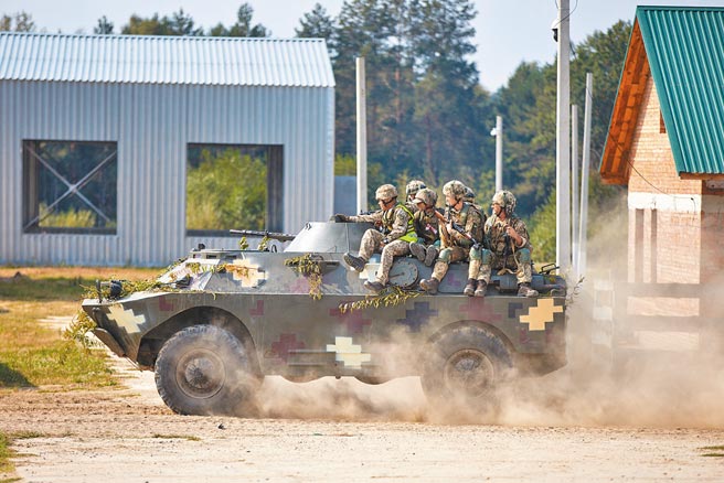 去年9月在乌克兰利沃夫州举行的多国联合军事演习中，一辆载着士兵的乌克兰装甲车正快速前进。乌克兰东部紧张情势升高，英美欧对俄罗斯部队在乌东边境集结相当关切。（新华社）